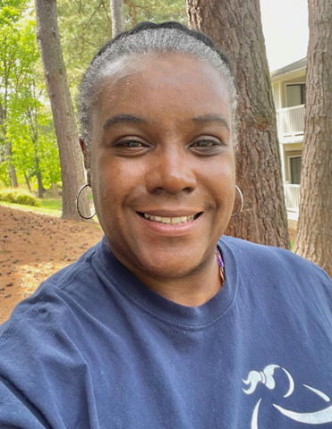 A Girls on the Run program coach smiles away from camera while wearing a purple shirt.