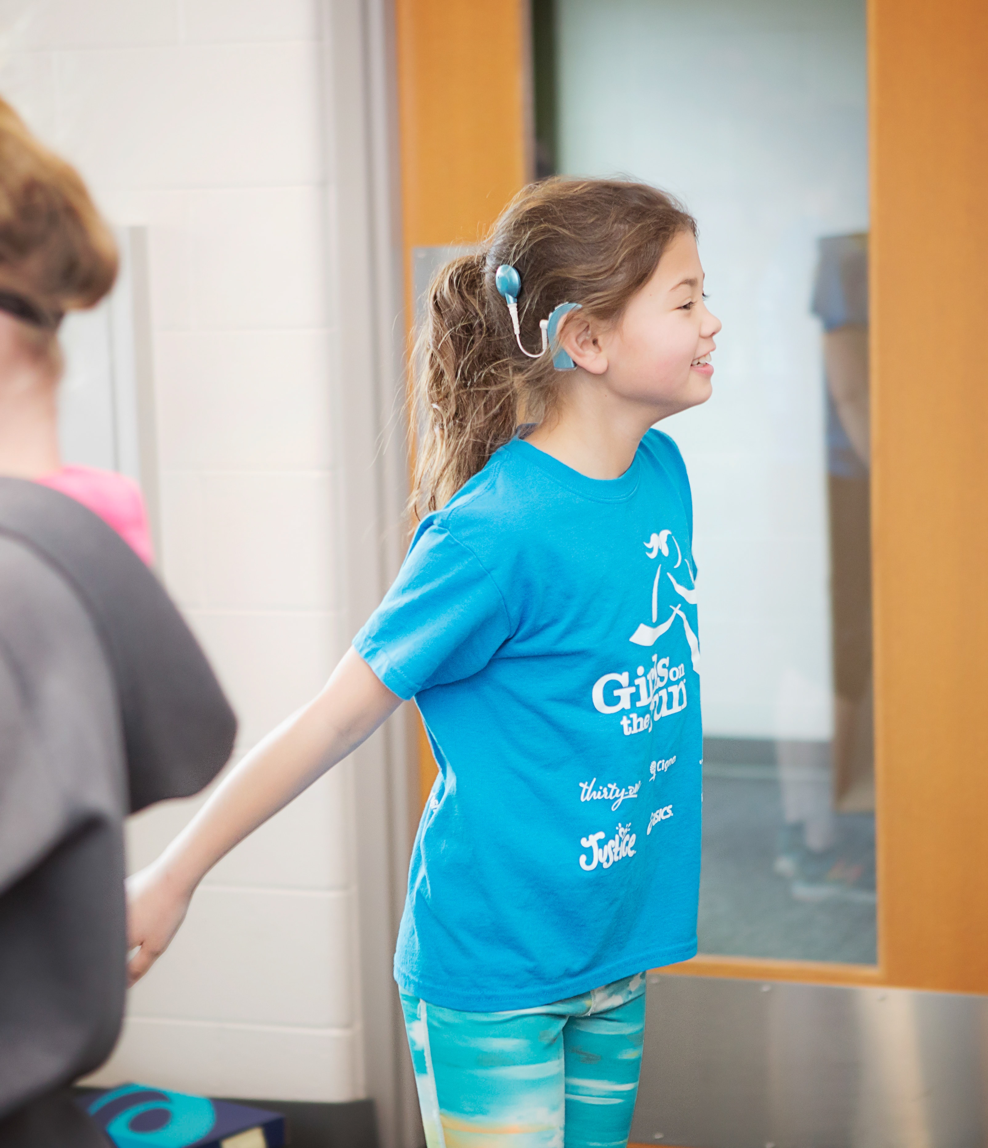 Girls on the Run participant wearing a hearing assisting device smiles during program practice